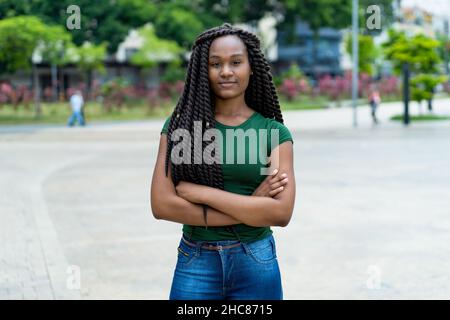 Giovane donna adulta dall'Africa con un'incredibile acconciatura all'aperto in estate in città Foto Stock