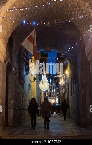 Gerusalemme, Israele. 25th Dic 2021. La gente cammina lungo una strada del Patriarcato greco decorata a Natale nel quartiere cristiano della città vecchia il 25 dicembre 2021 a Gerusalemme, Israele. Gli israeliani hanno limitato a viaggiare all'estero, a causa dell'impennata della variante Omicron COVID-19, che riempiva i vicoli a tema natalizio del quartiere cristiano. Credit: Eddie Gerald/Alamy Live News Foto Stock