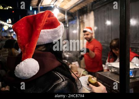 Gerusalemme, Israele. 25th Dic 2021. La gente compra il cibo tradizionale di Natale lungo la via di Bab el Gadid nel quartiere cristiano della città vecchia il 25 dicembre 2021 a Gerusalemme, Israele. Gli israeliani hanno limitato a viaggiare all'estero, a causa dell'impennata della variante Omicron COVID-19, che riempiva i vicoli a tema natalizio del quartiere cristiano. Credit: Eddie Gerald/Alamy Live News Foto Stock