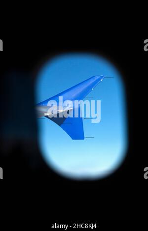 Aletta dell'airliner, vista da un sedile passeggero, guardando attraverso un oblò della fusoliera dell'aereo Foto Stock