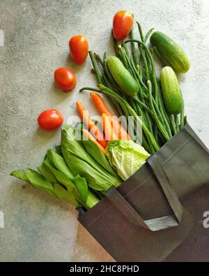 Vegetali ; covata di bok, cavolo cinese, carote, fagioli lunghi, cetrioli e pomodori in un sacchetto nero su un tavolo Foto Stock