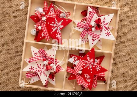 Un set di giocattoli di Natale in legno a forma di stella in una scatola di legno su imballaggio, primo piano, vista dall'alto. Foto Stock