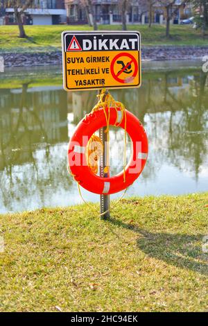 Life Buoy e cartello di avvertimento sul lungofiume in una giornata di sole in Turchia Foto Stock