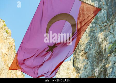 La bandiera turca soffia nel vento in una gola di montagna Foto Stock