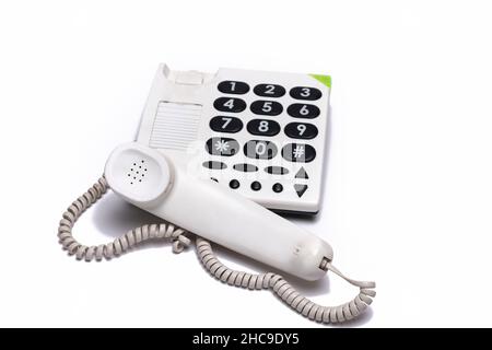 Primo piano del telefono fisso bianco con grandi pulsanti isolati su sfondo bianco Foto Stock
