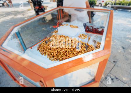 Mobile stalla per la vendita di mandorle fresche e succose su ghiaccio in vetrina. Uno spuntino buono e sano in una giornata calda, Foto Stock