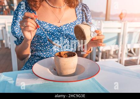 Giovane donna che mangia Testi kebab in ristorante su una terrazza. E' un autentico piatto di carne turco delizioso cotto in un vaso di argilla, servito dopo la rottura di t Foto Stock