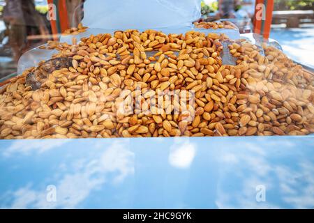 Mobile stalla per la vendita di mandorle fresche e succose su ghiaccio in vetrina. Uno spuntino buono e sano in una giornata calda, Foto Stock