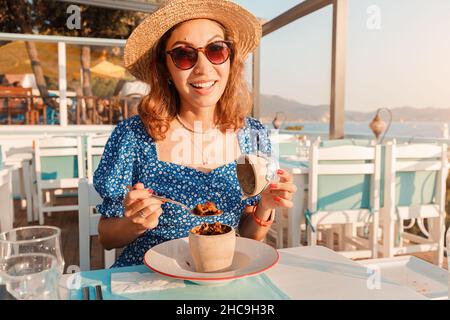 Giovane donna che mangia Testi kebab in ristorante su una terrazza. E' un autentico piatto di carne turco delizioso cotto in un vaso di argilla, servito dopo la rottura di t Foto Stock