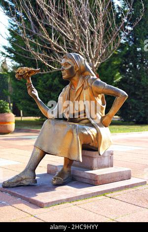 Statua di bronzo di una giovane donna con un bouquet di fiori a portata di mano che vende fiori all'aperto Foto Stock