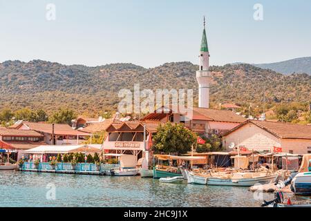 28 agosto 2021, Kaleucagiz, Turchia: Città costiera con barche da pesca, caffè e minareto moschea Foto Stock