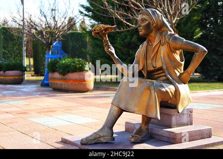 Statua di bronzo di una giovane donna con un bouquet di fiori a portata di mano che vende fiori all'aperto Foto Stock