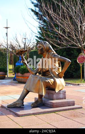 Statua di bronzo di una giovane donna con un bouquet di fiori a portata di mano che vende fiori all'aperto Foto Stock