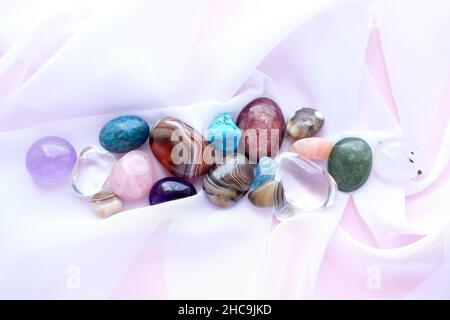 Gemme e cristalli tumbled e ruvidi di vari colori. Ametista, quarzo rosa, agato, apatite, aventurina, olivina, turchese, acquamarina, roccia cr Foto Stock