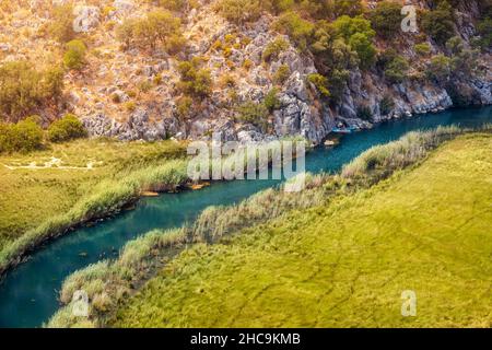 Vista aerea di un fiume tortuoso nel mezzo di una zona paludosa con un kayak che viaggia sul torrente Foto Stock