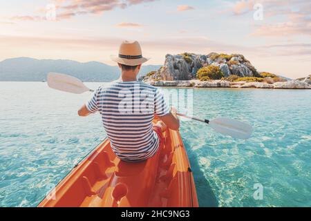 Uomo felice viaggiatore kayak vicino a un antico sarcofago e una tomba Licia nella città allagata di Kekova in Turchia. Una vacanza piacevole e salutare il giorno Foto Stock