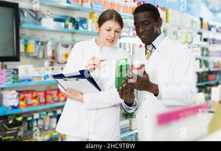 farmacisti che assumono l'inventario dei medicinali in farmacia Foto Stock