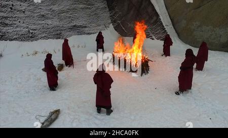 Processione fiaccolata. Fuoco rituale. Riprese. Gruppo di monaci in cappa a piedi lungo la pista invernale della neve in foresta. Gruppo di monaci in guood accappatoio Walkin Foto Stock