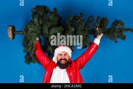 Uomo felice a Santa cappello con albero di Natale. Maschio bearded con albero nuovo dell'anno. Vendita e sconto. Foto Stock