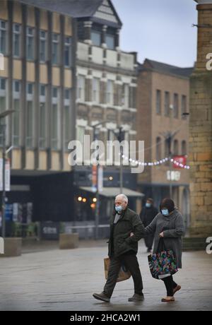 Peterborough, Regno Unito. 26th Dic 2021. I clienti che indossano maschere facciali come misura protettiva contro la diffusione di coronavirus trasportano i sacchetti di shopping che contengono le merci durante il giorno di boxe sales.The strade sono estremamente tranquille il giorno di boxe, con pochissimi acquirenti come le vendite iniziano nei negozi nel centro di Peterborough. Credit: SOPA Images Limited/Alamy Live News Foto Stock