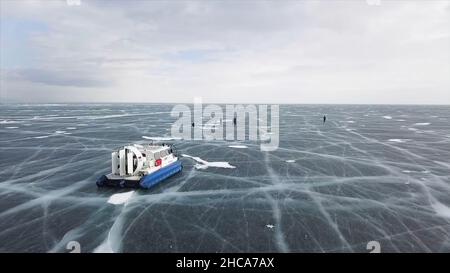 Vista aerea della macchina in movimento sul lago ghiacciato sorprendente. Tipico veicolo hovercraft su una superficie di ghiaccio limpido e ghiacciato, Lago Baikal, Siberia, Russia. Foto Stock