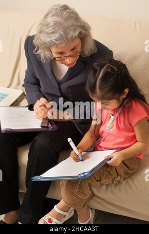 Ricercatore sulla visita domestica alla ragazza di tre anni che interagisce con lei e prendendo note la famiglia è ricercatore messicano americano è causcasico New York cit Foto Stock