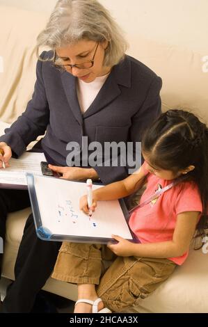 Ricercatore sulla visita domestica alla ragazza di tre anni che interagisce con lei e prendendo note la famiglia è ricercatore messicano americano è causcasico New York cit Foto Stock