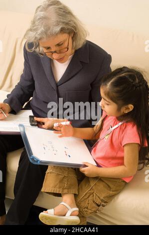 Ricercatore sulla visita domestica alla ragazza di tre anni che interagisce con lei e prendendo note la famiglia è ricercatore messicano americano è causcasico New York cit Foto Stock