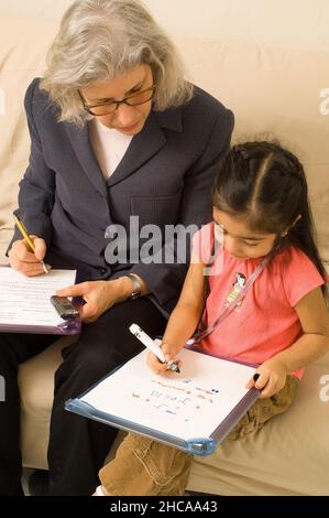 Ricercatore sulla visita domestica alla ragazza di tre anni che interagisce con lei e prendendo note la famiglia è ricercatore messicano americano è causcasico New York cit Foto Stock