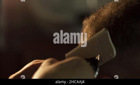 L'uomo ottiene un taglio freddo dei capelli nel barbiere. Telaio. Mani di capelli professionale stylist taglio capelli cliente scatto. Primo piano della mano dell'estetista con le forbici Foto Stock