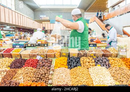 Un uomo che vende frutta secca e noci al mercato verde bazar bazar, il più grande e più antico mercato al coperto di Almaty, Kazakhstan Foto Stock