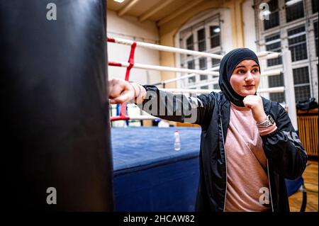 16 dicembre 2021, Berlino: Allenatore di pugilato Doha Taha Beydoun si leva nella pratica di boxe in palestra. Ha solo 20 anni. Sposato. Quattro mesi di gravidanza. Musulmano e un addestratore di boxe. I suoi genitori emigrarono dal Libano alla Germania quando era una bambina. Doha Taha Beydoun sembra 'strange' ad alcuni, dice, perché la sua nazionalità, religione e sport non corrispondono. Altri la vedono come un modello di ruolo, come lei stessa dice. "Combatto contro tutti i pregiudizi", la giovane donna si dona con fiducia. (Al dpa 'Muslim, donna, allenatore di pugilato - 'combatto contro tutti i pregiudizi') Foto: Fabian Sommer/dpa Foto Stock