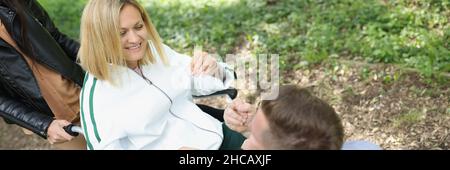 L'uomo comunica con una donna sorridente in sedia nel parco Foto Stock