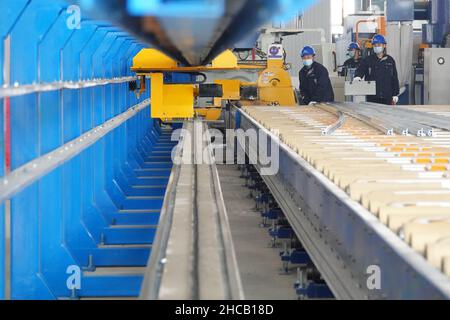 YANTAI, CINA - 27 DICEMBRE 2021 - Un lavoratore produce materiali leggeri presso il Centro di innovazione Automotive Lightweight di Yantai, Shandong Provin Foto Stock