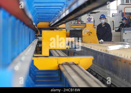 YANTAI, CINA - 27 DICEMBRE 2021 - Un lavoratore produce materiali leggeri presso il Centro di innovazione Automotive Lightweight di Yantai, Shandong Provin Foto Stock