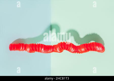 Il tubo pop curvo è appoggiato contro la parete. Vita morta moderna con giocattolo antistress. Foto Stock