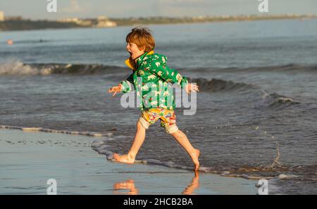 Sandbanks, Regno Unito. 26th dicembre 2021. Jesse Nathaniel,5, trovò l'acqua un po' gelida per il suo gradimento, mentre il sole luminoso vide la folla che si aggirava sulla spiaggia il giorno di Santo Stefano a Sandbanks a Poole, Dorset nonostante alcune anime dure che si sfidavano il freddo per fare delle salse in mare. Credit: Richard Crease/Alamy Live News Foto Stock