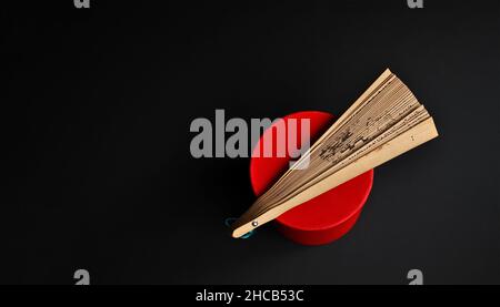 Ventilatore in legno orientale e scatola blu su sfondo scuro Foto Stock