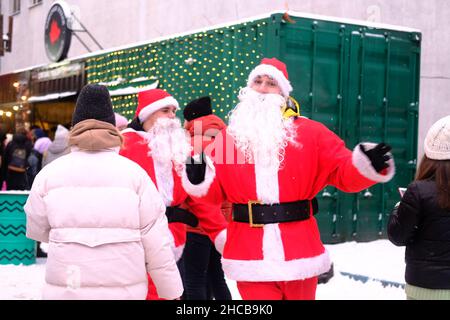 Minsk, Bielorussia, 25 dicembre 2021: Due Babbo Natale camminano allegro tra la gente alla fiera di Capodanno. Foto Stock