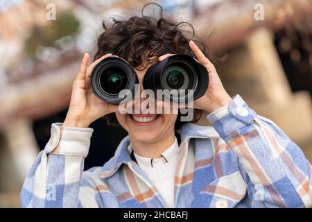 Giovane bruna capelli ricci donna fotografando intorno con due obiettivi Foto Stock