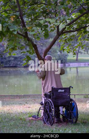 Un seguace americano cinese di 86 anni di Falun Gong fa esercizi lenti di fronte ad un albero in un parco a Queens, New York City. Foto Stock