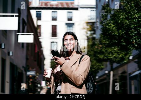 Donna d'affari sorridente con smartphone in città Foto Stock