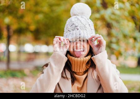 Donna giocosa con cappello a maglia che attacca la lingua al parco Foto Stock