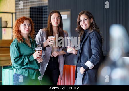 Una donna d'affari felice che tostava bevande con i colleghi al bar Foto Stock