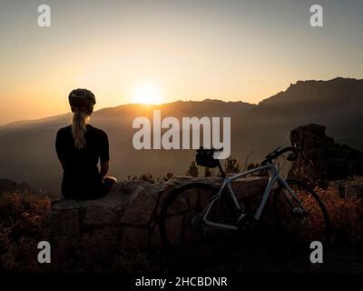 Sport swoman seduto su roccia e guardando il tramonto Foto Stock