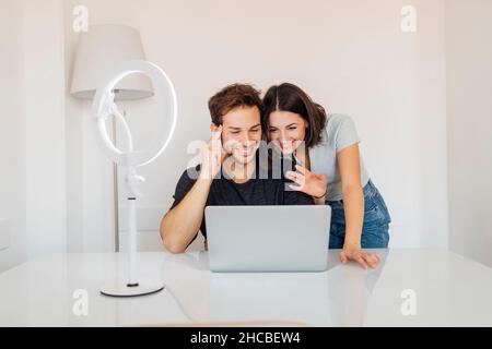 Giovane coppia di freelance che lavora insieme su un notebook in ufficio a casa Foto Stock