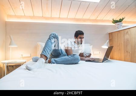 Uomo d'affari che usa il laptop a letto in soffitta a casa Foto Stock