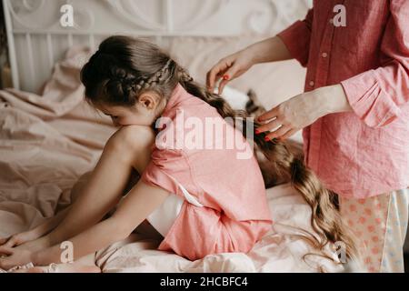 Donna che brucia i capelli della figlia in camera da letto Foto Stock