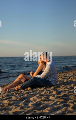 Coppia giovane seduti insieme sulla spiaggia Foto Stock