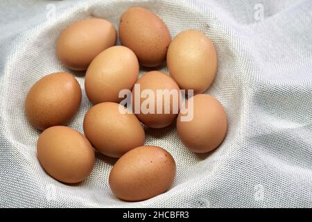 Uova di pollo fresche e marroni nel cestino di vimini Foto Stock